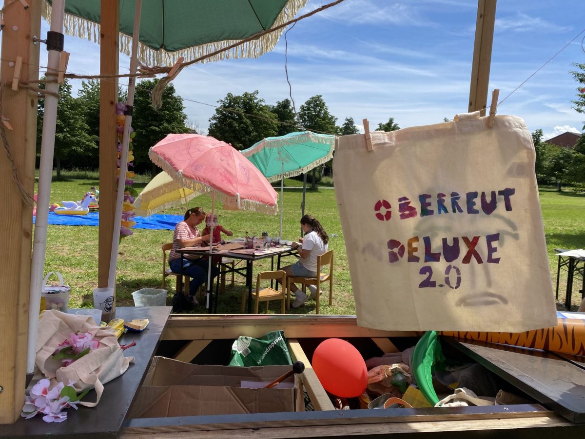 Eine selbstbedruckte Tasche trocknet im Vordergrund und im Hintergrund malen und basteln drei Personen beim Bürger-Café in Oberreut.