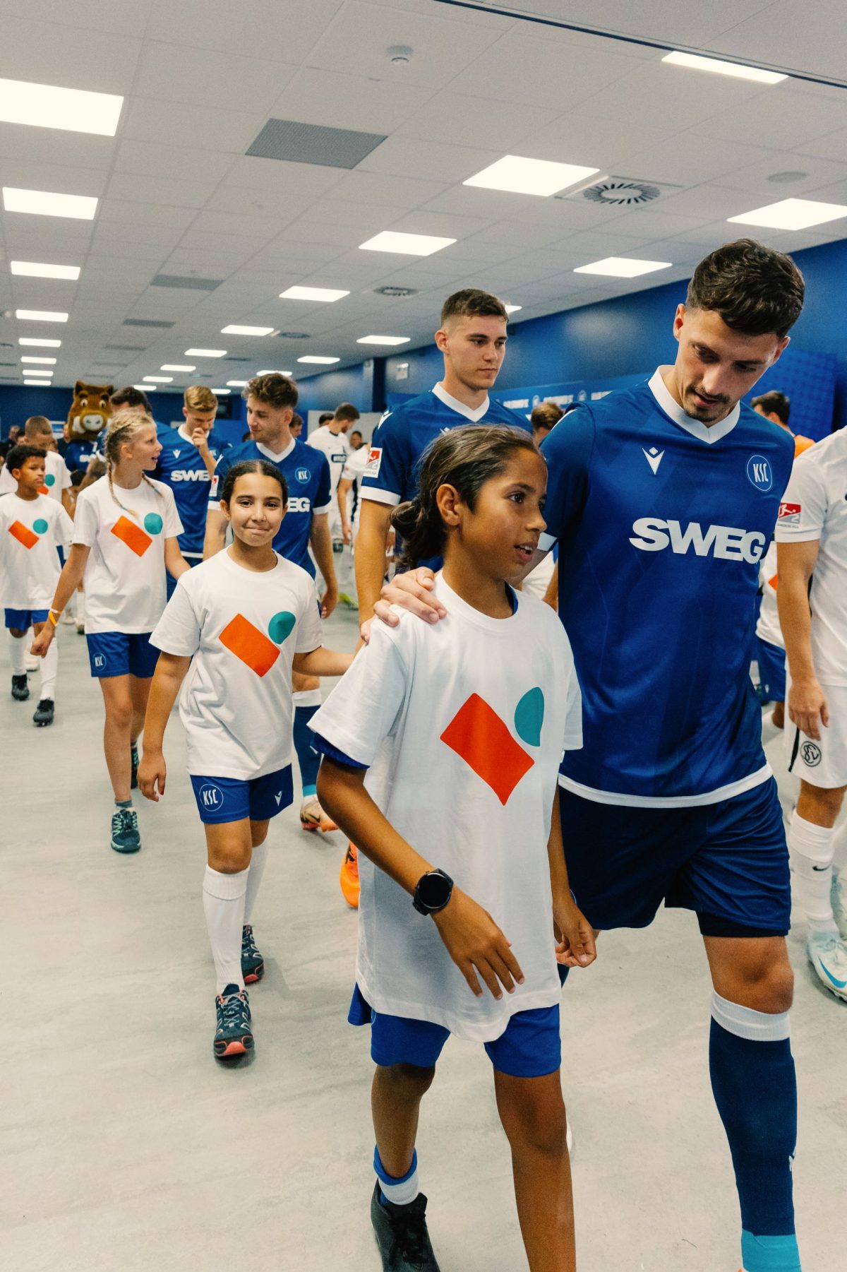Kinder aus unserer Mieterschaft laufen mit den KSC-Spielerin ein zum Spiel.