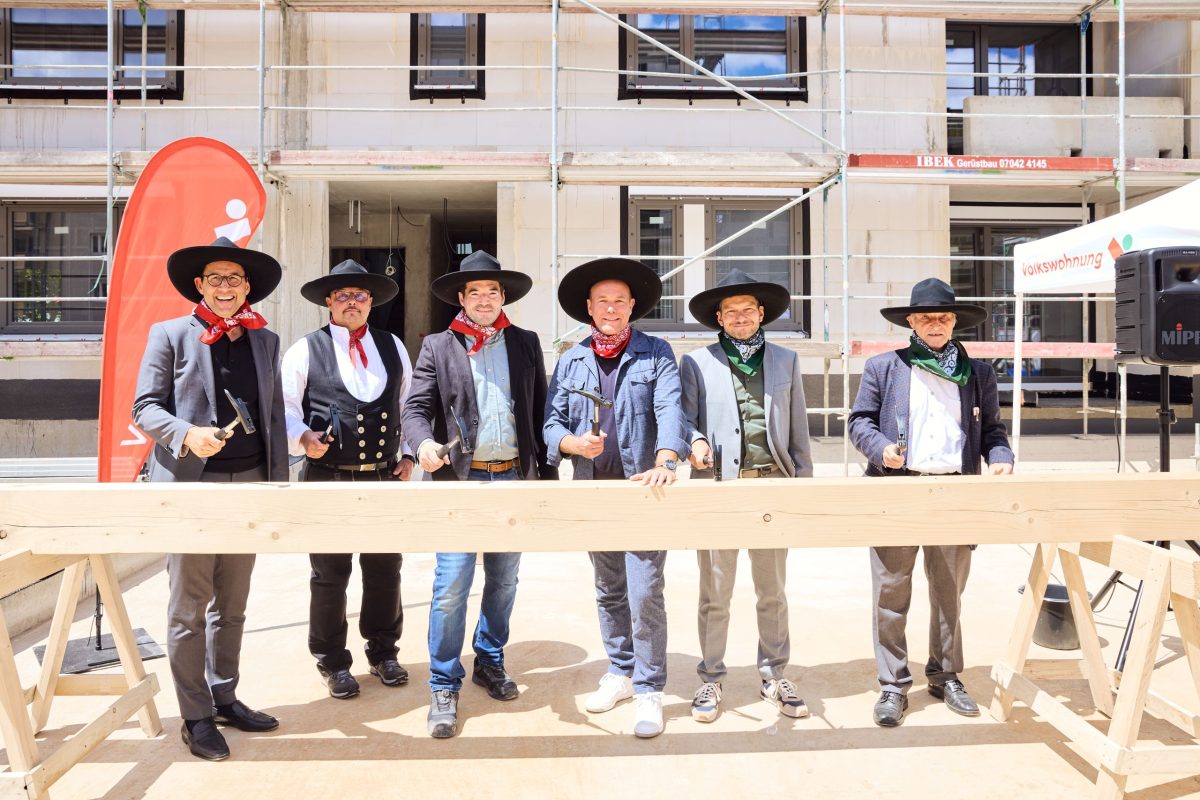 Sechs Männer schlagen symbolisch zum Richtfest Nägel ins Holz.