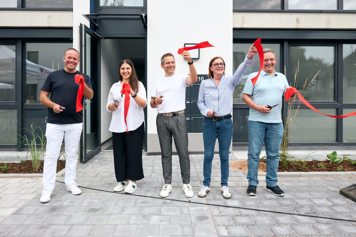 Fünf Personen schneiden symbolisch das Band zur Fertigstellung des Neubauprojekts durch.