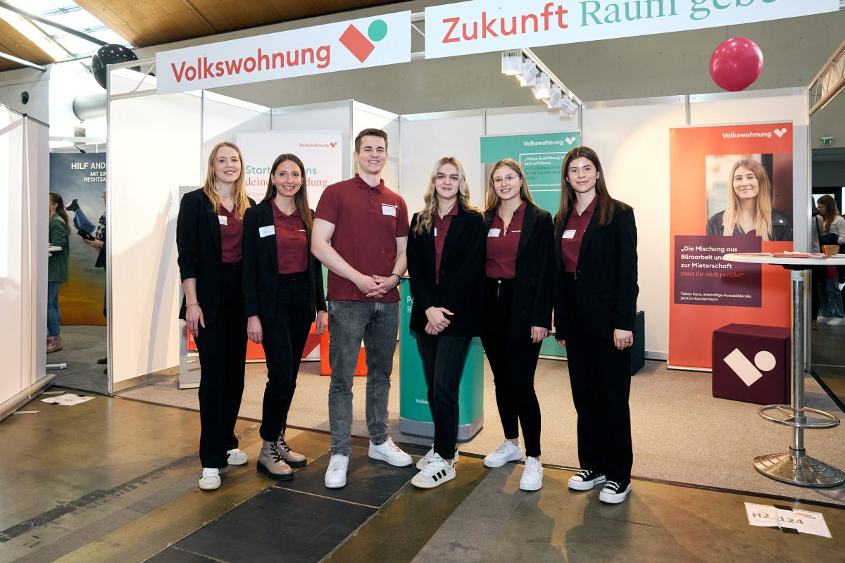 Team der Volkswohnung steht gemeinsam vor einem Messestand und präsentiert Informationsangebote zu Ausbildung und Berufseinstieg.